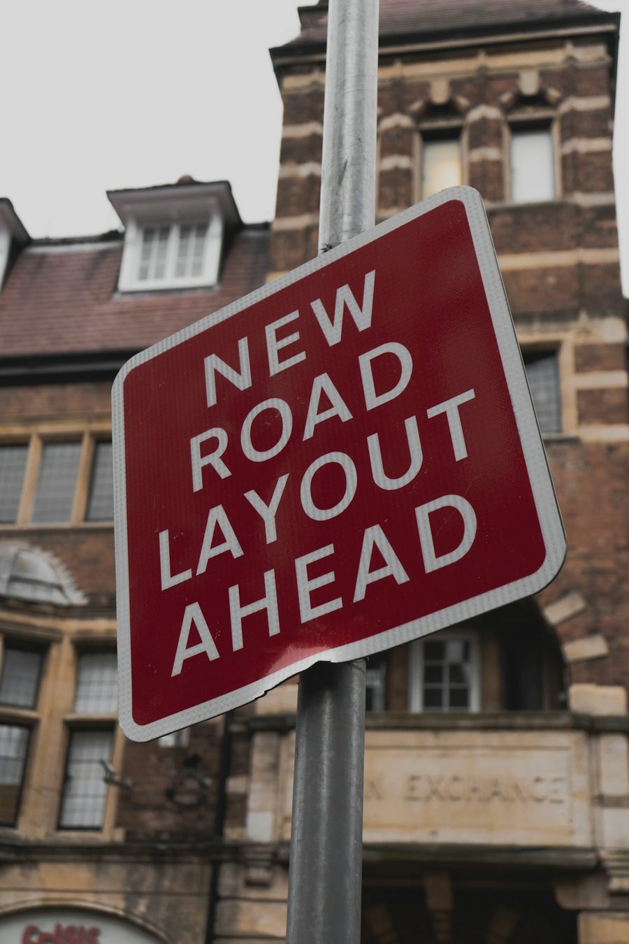 A red British road sign reading New Road Layout Ahead.